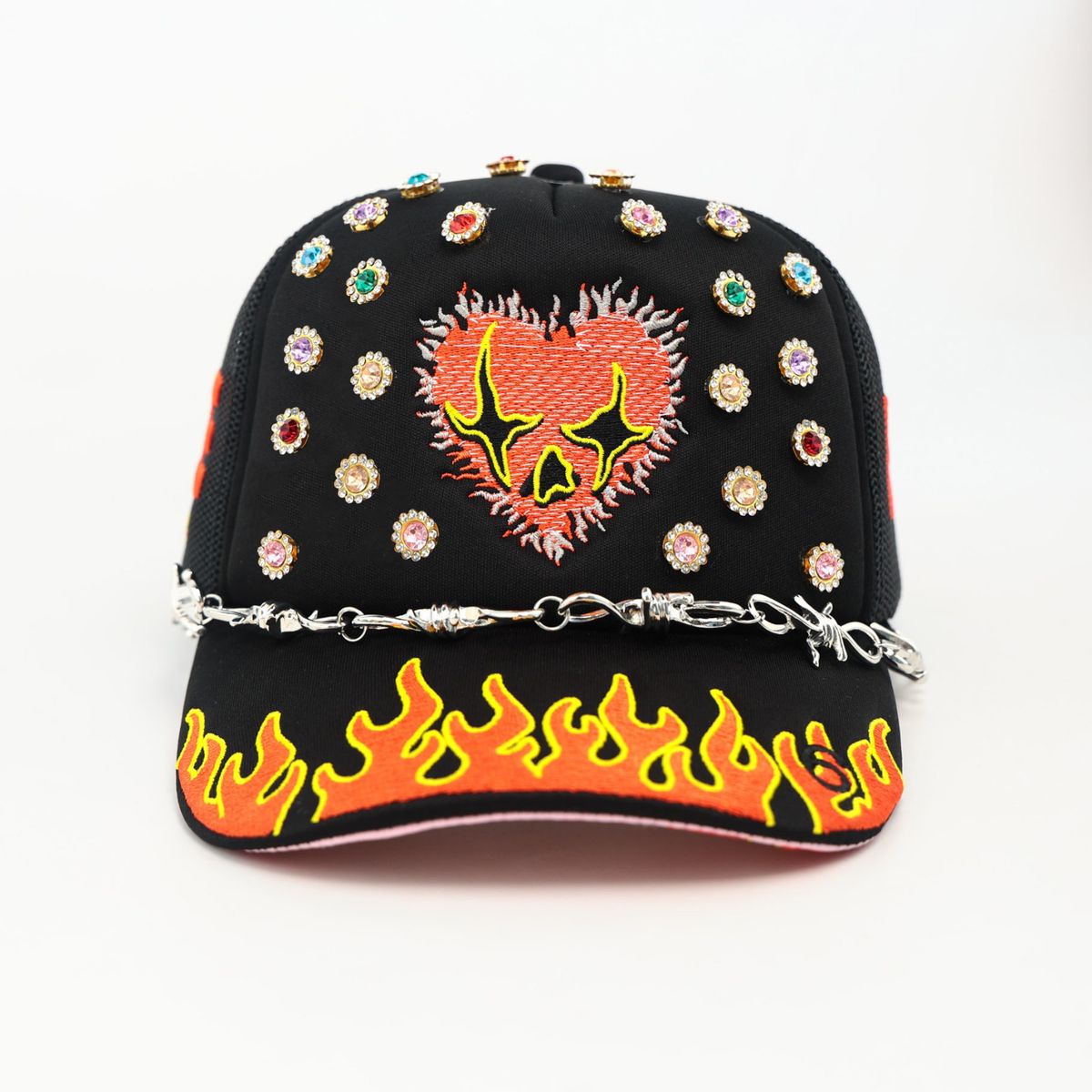 Black cap with colorful heart design, flames, and embellishments on a white background