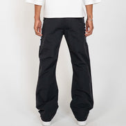 A person shown from the back wearing black wide-leg cargo pants with white sneakers and a white top, photographed against a plain light gray studio background.