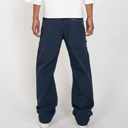 A person shown from the back wearing dark navy wide-leg pants with a white t-shirt and white sneakers, standing against a light gray studio background.