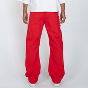 A person shown from the back wearing bright red wide-leg pants and a white T-shirt against a light gray studio background.