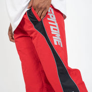 Red and black track pants with white 'EPITOME' text on the leg and a white 'Gatm.' logo near the hem, shown on a model wearing a white t-shirt against a white studio background.