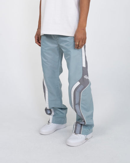 Light blue track pants with white and gray stripes worn by a person on a white background