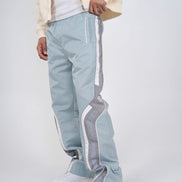 Light blue track pants with white stripes worn by a person on a light gray background