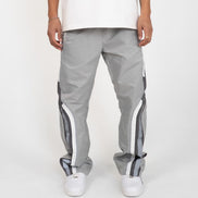 Person wearing gray track pants with white stripes on a white background