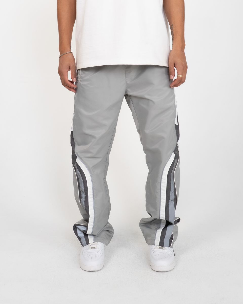 Person wearing gray track pants with white stripes on a white background