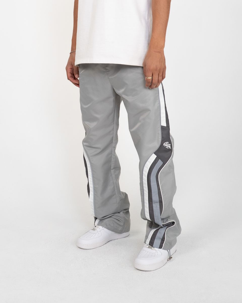Person wearing gray track pants with white stripes on a white background