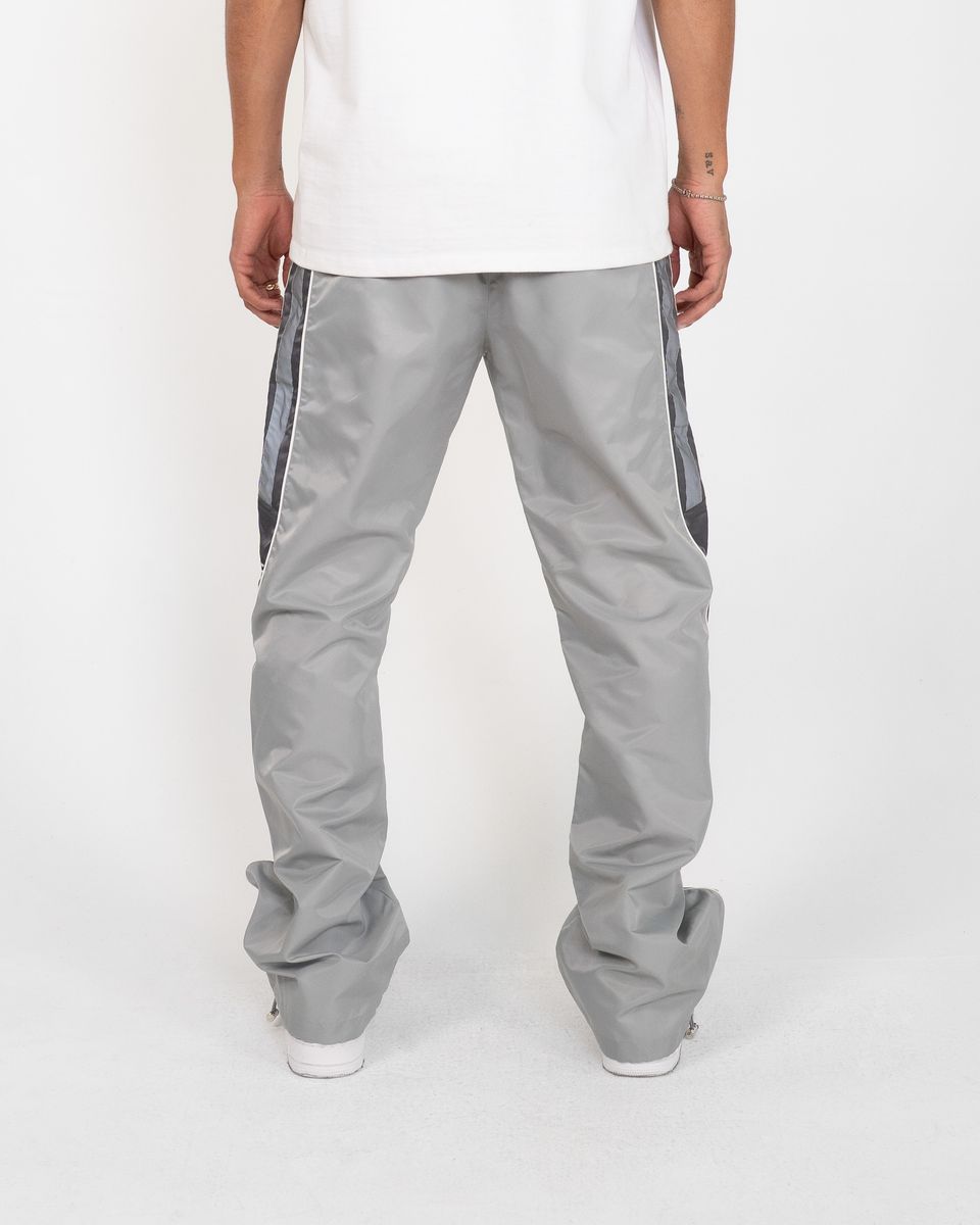 Person wearing gray pants with side stripes on a white background