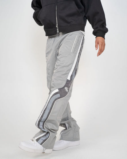 Person wearing gray track pants with white stripes on a white background