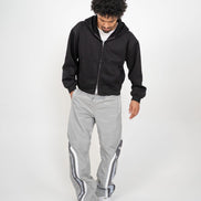 Person wearing a black hoodie and gray tracksuit with white stripes on a white background