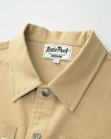 Close-up of a beige shirt collar with a visible brand label on a light gray background