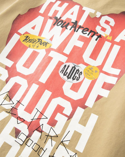 Beige sweatshirt with red graphic and text, featuring visible brand logos.