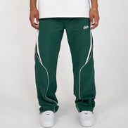 Green track pants with white accents worn by a person on a white background