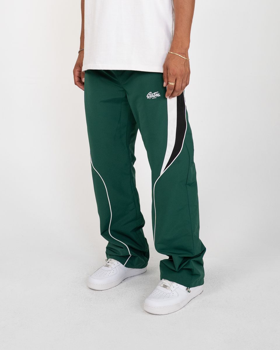 Green track pants with white and black accents worn by a person on a white background