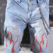 Blue denim shorts with red flame designs and a chain detail worn by a person.