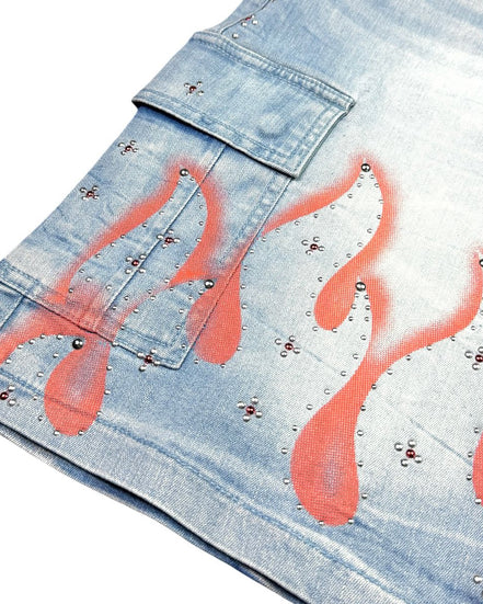 Denim shorts with flame designs and studs on a white background