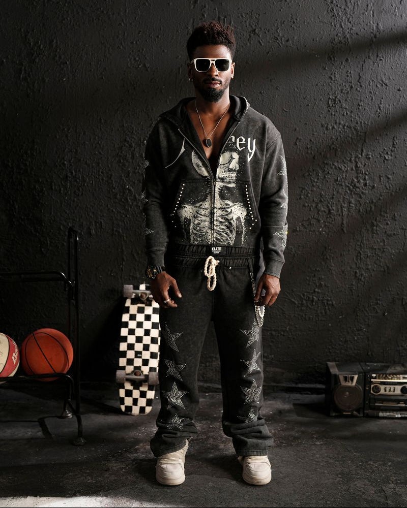 Man wearing sunglasses and a hoodie standing in a room with sports balls and equipment.