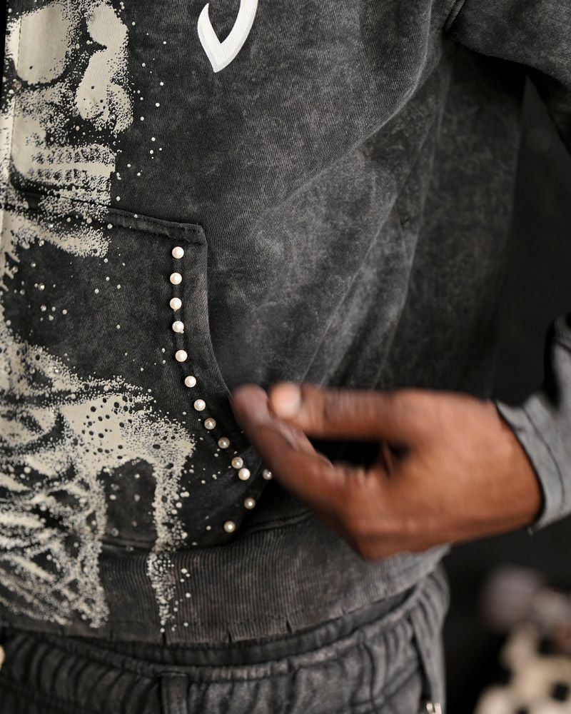 Person wearing a black jacket with studded details on a blurred background