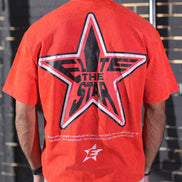 Person wearing a red t-shirt with a star design and text on the back.