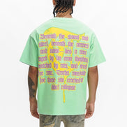 Person wearing a light green t-shirt with text and a yellow design on the back, standing against a white background.