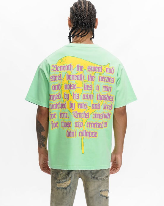 Person wearing a light green t-shirt with text and a yellow design on the back, standing against a white background.