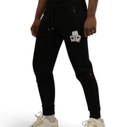 Person wearing black jogger pants with card design patches on a white background