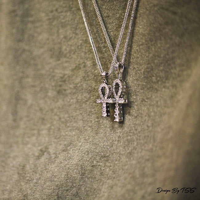 Silver necklaces with an ankh pendant on a textured surface