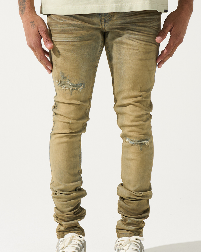 Person wearing beige distressed jeans and white sneakers on a white background