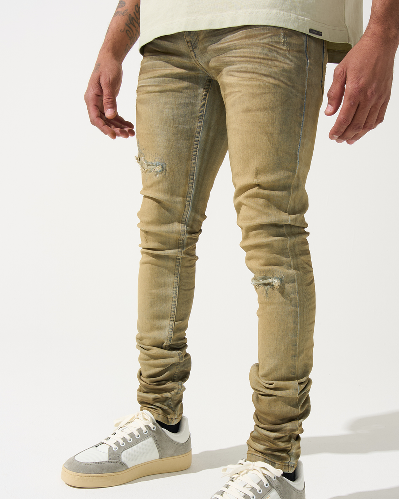 Beige distressed jeans worn by a person on a white background
