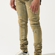 Person wearing beige distressed jeans and gray sneakers on a white background
