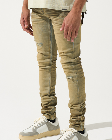 Person wearing beige distressed jeans and gray sneakers on a white background