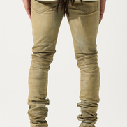 Person wearing beige jeans and white sneakers on a plain background