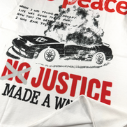 White graphic t-shirt featuring a distressed black and red print with the text 'no peace NO JUSTICE MADE A WAY' and an image of a smoking car.