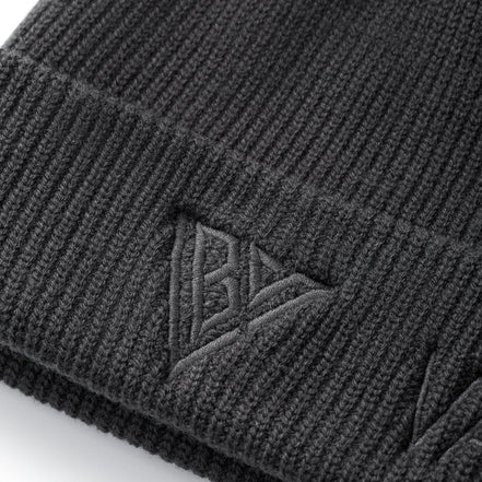 Close-up of a dark charcoal gray ribbed knit beanie with an embossed Valabasas flag logo on the cuff.