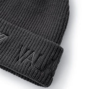Close-up of a dark gray ribbed knit beanie with a folded cuff and tonal embroidered logo on a white background.