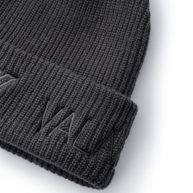 Close-up of a dark gray ribbed knit beanie with a folded cuff and tonal embroidered logo on a white background.