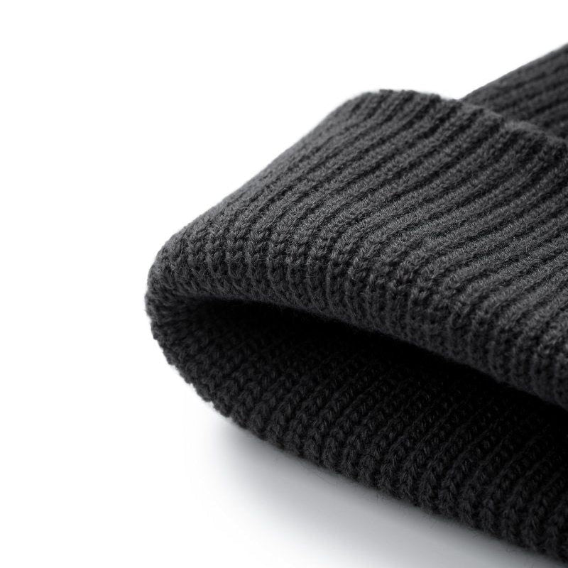 A close-up of a folded dark grey ribbed knit beanie hat on a clean white background.