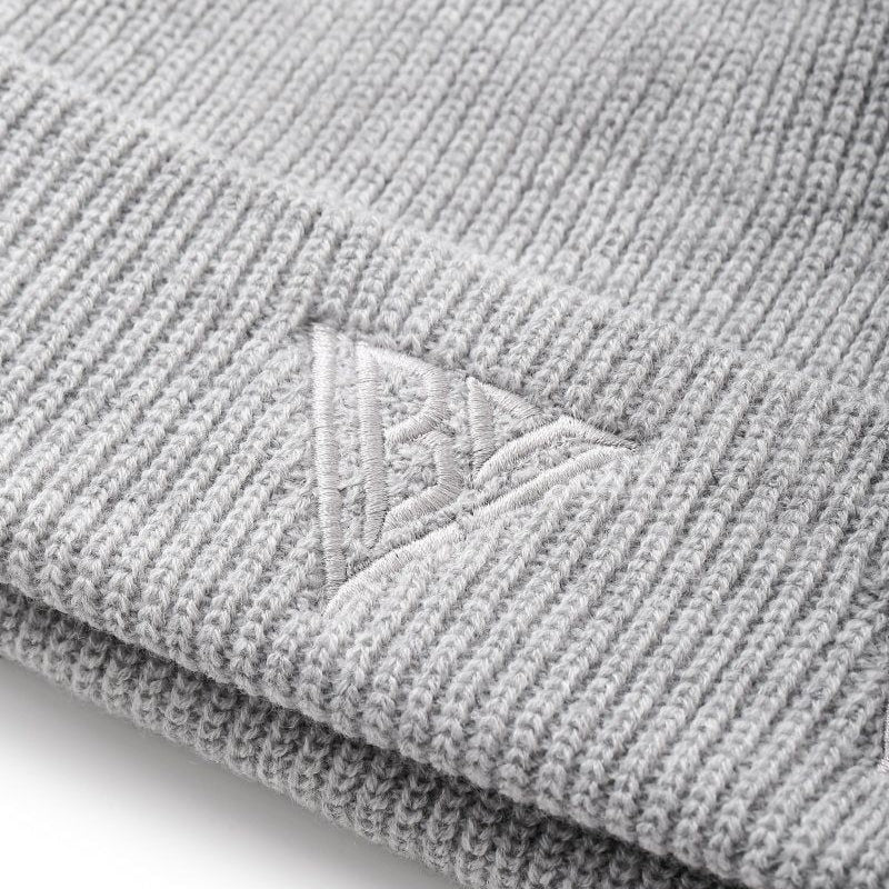 Close-up of a gray knit beanie with a brand logo on a white background