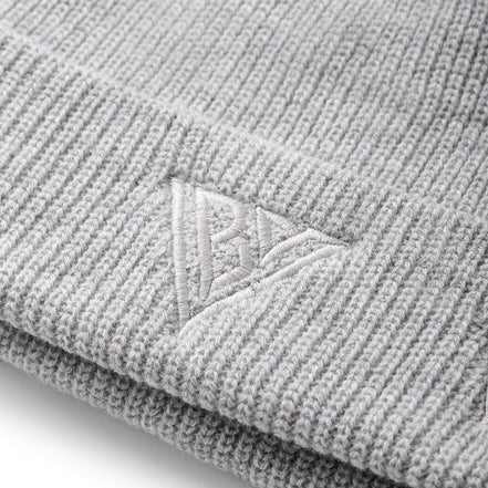 Close-up of a gray knit beanie with a brand logo on a white background