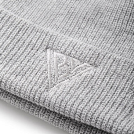 Close-up of a gray knit beanie with a brand logo on a white background