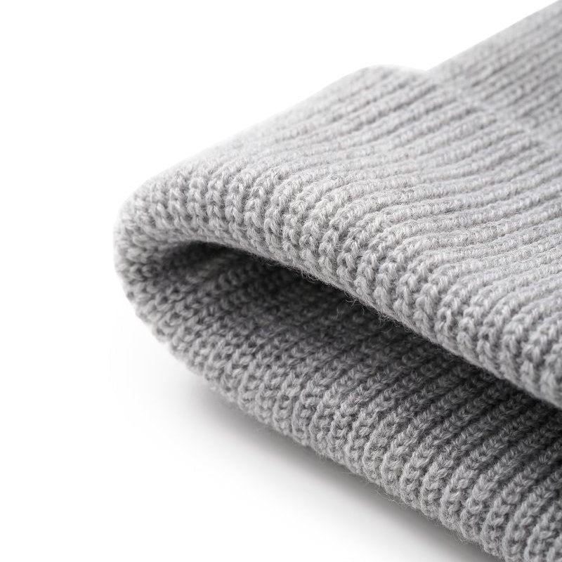 A close-up of a folded light gray ribbed knit fabric, showing the texture and weave detail against a clean white background.