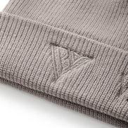 Close-up of a beige knit beanie with a logo on a white background