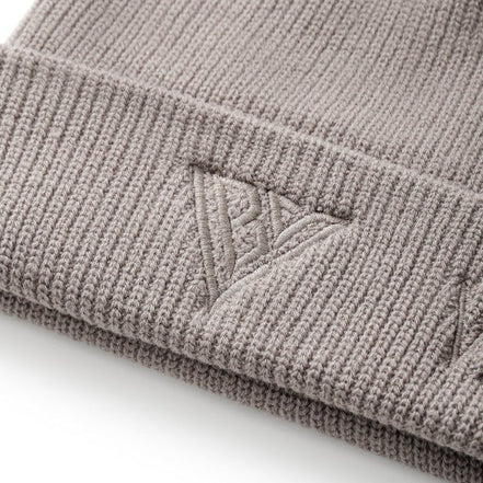 Close-up of a beige knit beanie with a logo on a white background