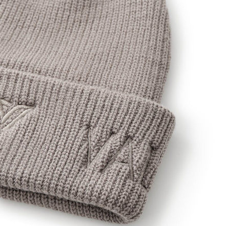 Folded beige knit beanie on a white background