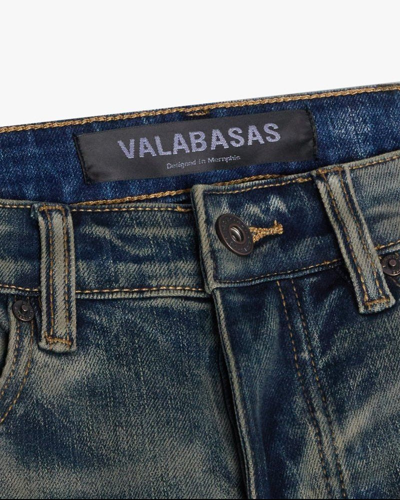 Close-up of blue jeans with a visible brand label on a white background