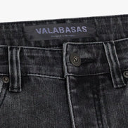 Close-up of a grey denim pocket with 'VALABASAS' branding on a white background