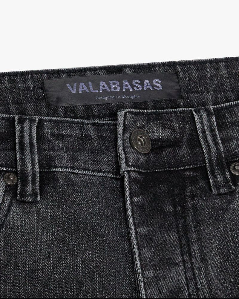 Close-up of a grey denim pocket with 'VALABASAS' branding on a white background