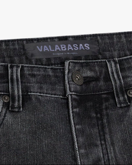 Close-up of a grey denim pocket with 'VALABASAS' branding on a white background