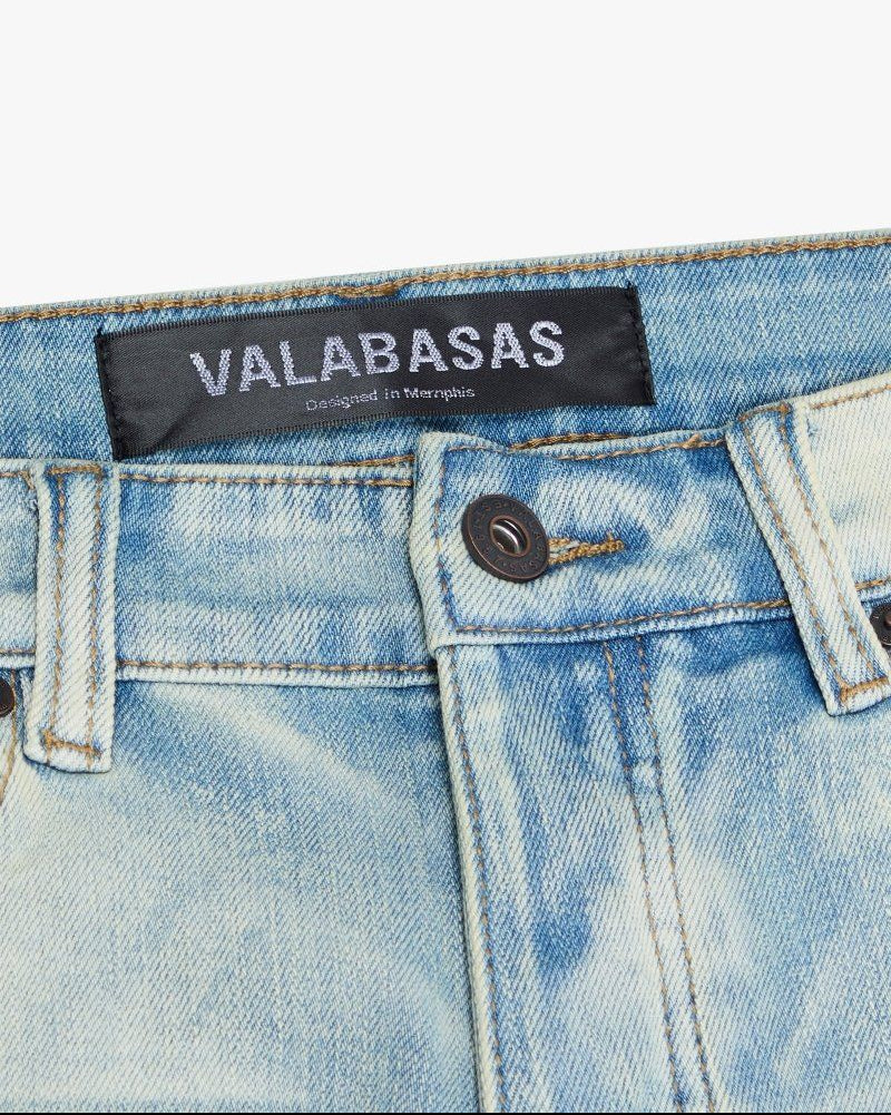 Close-up of a denim garment with 'VALABASAS' label on a white background