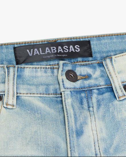 Close-up of a denim garment with 'VALABASAS' label on a white background
