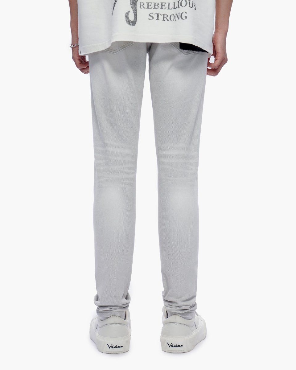 Person wearing light gray pants and a white shirt with text on a white background